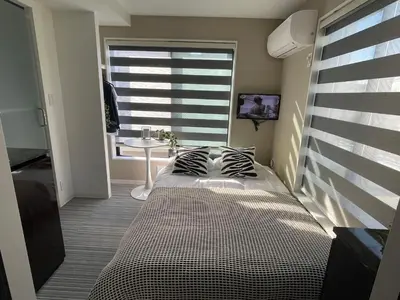 a bedroom with a bed and a window with a table at COMMA HOUSE Shinjuku 402 in Tokyo
