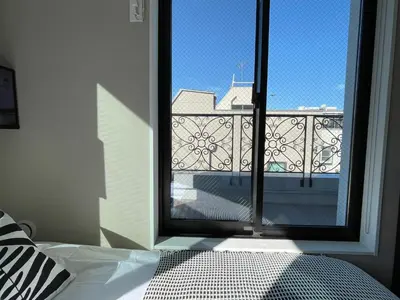 a bedroom with a window with a view of a balcony at COMMA HOUSE Shinjuku 402 in Tokyo