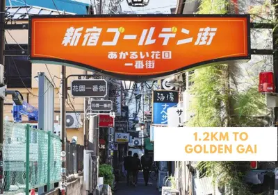 an orange sign on a city street with signs at COMMA HOUSE Shinjuku 402 in Tokyo