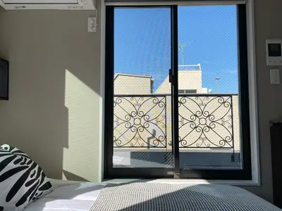a bedroom with a window with a view of a balcony at COMMA HOUSE Shinjuku 402 in Tokyo