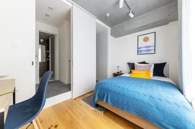 a bedroom with a bed and two blue chairs at Dash Living Kagurazaka in Tokyo