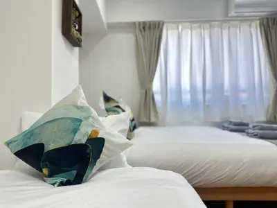 a bedroom with two beds with white sheets and a window at nestay miriz tokyo ikebukuro in Tokyo