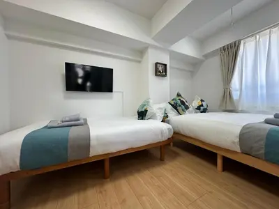 two beds in a room with a tv on the wall at nestay miriz tokyo ikebukuro in Tokyo