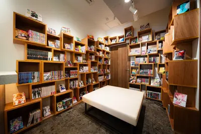 a library with a white bench in front of bookshelves at MANGA ART HOTEL, BAKUROCHO in Tokyo