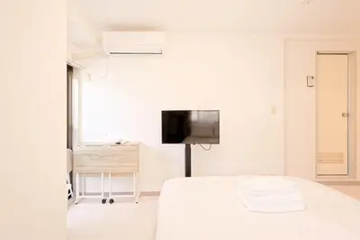a white bedroom with a bed and a flat screen tv at Mi-APT SHIRO in Tokyo
