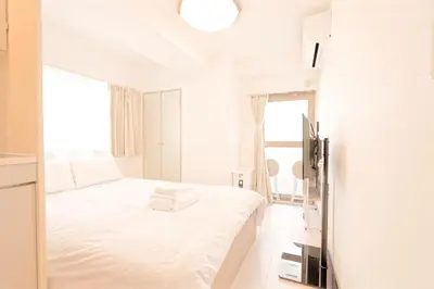 a white bedroom with a bed and a window at Mi-APT SHIRO in Tokyo