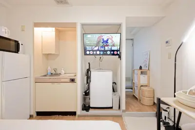 a kitchen with a refrigerator and a tv on the wall at Mi-APT SHIRO in Tokyo