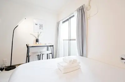 a white bedroom with a bed and a desk at Mi-APT SHIRO in Tokyo