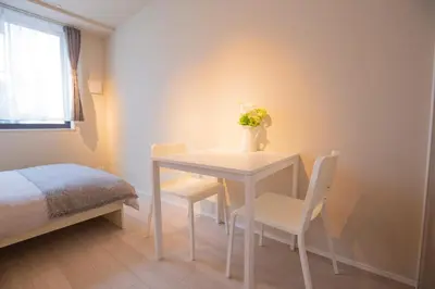a white table and chairs with a vase of flowers on it at The most comfortable and best choice for accommodation in Yoyogi YoEK in Tokyo