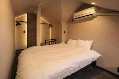 a bedroom with a white bed and a air conditioner at \u30eb\u30fc\u30c1\u30a7\u897f\u65b0\u5bbf in Tokyo