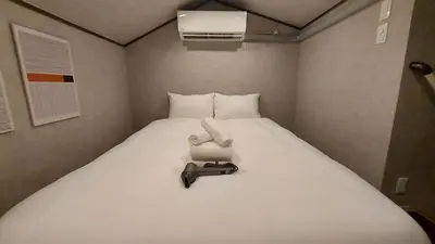 a small bedroom with a large white bed at \u30eb\u30fc\u30c1\u30a7\u897f\u65b0\u5bbf in Tokyo