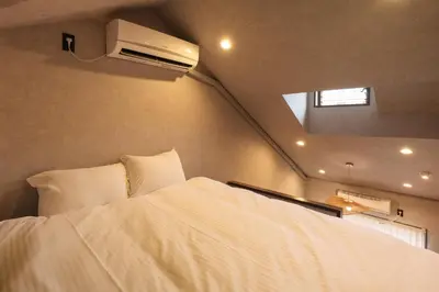 a bedroom with a white bed and a air conditioner at \u30eb\u30fc\u30c1\u30a7\u897f\u65b0\u5bbf in Tokyo