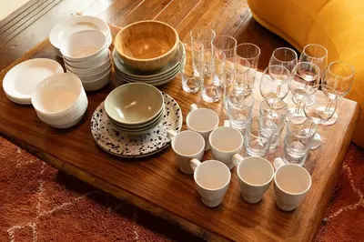 a wooden table topped with glasses and plates and bowls at The Archaic / Luxury apartment near Shinjuku in Tokyo
