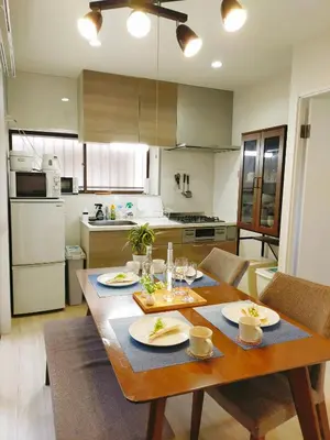 a kitchen with a wooden table with dishes on it at 15min to Haneda Airport - Homies House Kamata for up to 9 guests in Tokyo