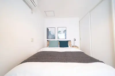 a white bedroom with a large bed with blue pillows at FINOA Residential Suite Horikiri in Tokyo
