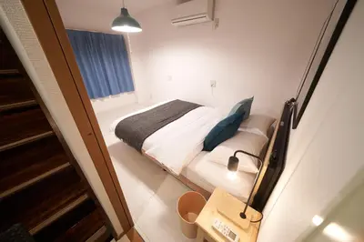 a bedroom with a bed with blue pillows at FINOA Residential Suite Horikiri in Tokyo