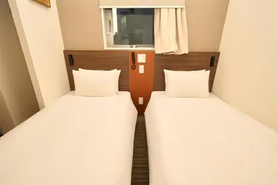 two twin beds in a small room with a window at Nplus HOTEL Tokyo Nihonbashi in Tokyo