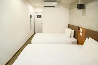 two beds in a small room with white walls at Nplus HOTEL Tokyo Nihonbashi in Tokyo