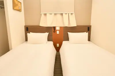 two beds in a small room with white sheets at Nplus HOTEL Tokyo Nihonbashi in Tokyo