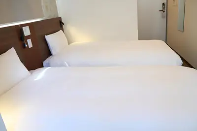 two beds in a hotel room with white sheets at Nplus HOTEL Tokyo Nihonbashi in Tokyo