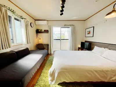 a bedroom with a bed and a couch and a window at Shimokitazawa Akima in Tokyo