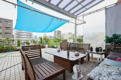 a patio with a table and chairs and an umbrella at \u6d45\u8349\u685c\u6a4b\u30cf\u30a4\u30c4 Asakusa Sakurabashi\u3000 2F in Tokyo