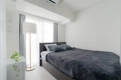 a white bedroom with a bed and a window at unito residence HIGASHISHINJUKU in Tokyo