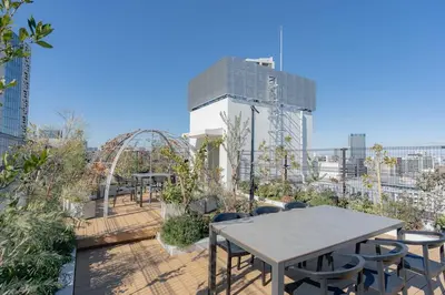 a patio with tables and chairs on top of a building at unito residence HIGASHISHINJUKU in Tokyo