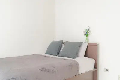 a bed with two pillows and a vase of flowers on it at unito residence WASEDA in Tokyo
