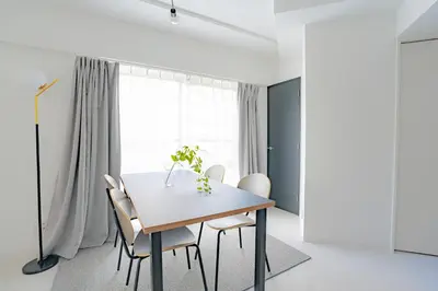 a white dining room with a table and chairs at unito residence OTSUKA in Tokyo
