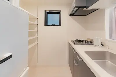 a white kitchen with a sink and a counter top at unito residence OTSUKA in Tokyo