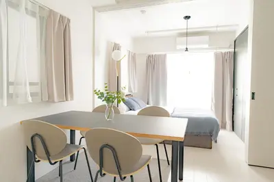 a dining room with a table and chairs and a bed at unito residence OTSUKA in Tokyo