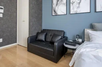 a black leather couch in a bedroom next to a bed at Felice Nishi-Shinjuku in Tokyo