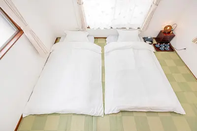 two beds in a room with white sheets at Himawari in Tokyo
