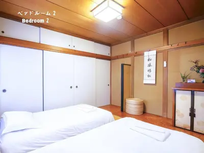 two beds in a room with a sign on the wall at 7\u6642IN19\u6642OUT # \u6c60\u888b\u738b\u5b50\u8d64\u7fbd\u99c5\u7121\u6599\u9001\u8fce # \u4e0a\u91ce\u99c514\u5206 # \u4e00\u68df\u8cb8\u3057 # 2LDK2LDK # \u6700\u592724\u4eba # 7 00 IN19 00 OUT # Free pick-up at Ikebukuro, Oji, and Akabane Stations # 14 min to Ueno # Whole house rental # 2LDK2LDK # Max 24 in Tokyo
