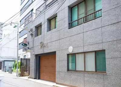 a gray building with a wooden door on a street at \u30d7\u30ea\u30cd\u30c3\u30c4\u65b0\u5bbf\u30d3\u30eb3\u968e in Tokyo