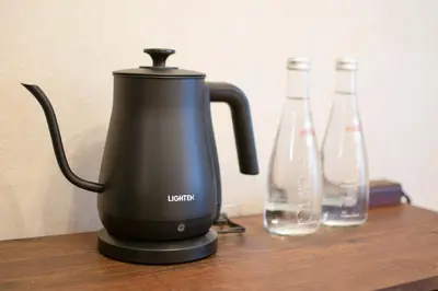 a black kettle sitting on a table with two bottles at Fuufu House Tokyo Ikebukuro in Tokyo