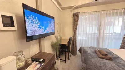 a bedroom with a flat screen tv on the wall at Fuufu House Tokyo Ikebukuro in Tokyo