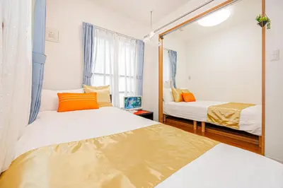 a bedroom with two beds and a mirror at KYARA Hotel 402 in Tokyo