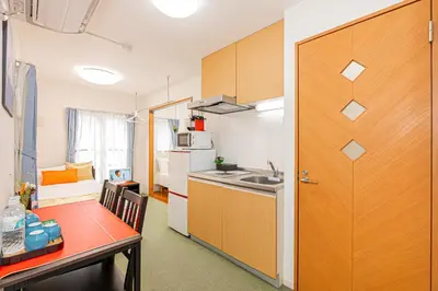 a kitchen with a table and a sink and a door at KYARA Hotel 402 in Tokyo