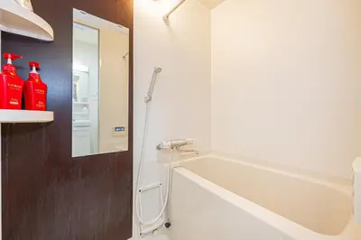a bathroom with a bath tub and a mirror at KYARA Hotel 402 in Tokyo