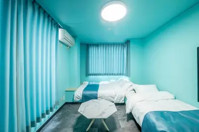 a blue room with two beds and a table at YOYOGI PARK HOTEL in Tokyo
