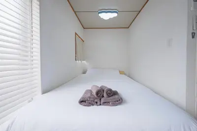 a white bed with two towels on it at Push house \u6d66\u5b89 in Tokyo