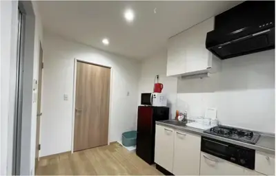 a kitchen with white cabinets and a black refrigerator at Tokyo Stay \u821e in Tokyo