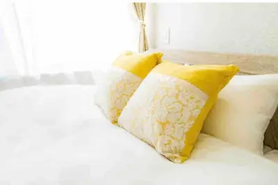 two yellow pillows on a white bed with a window at 55, Kameido-Suijin, Entire house for rent, \u4e80\u6238\u6c34\u795e in Tokyo