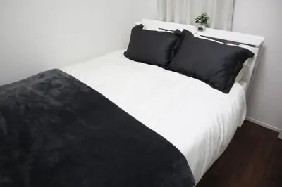 a white bed with black pillows in a bedroom at L\uff06L\uff08Love\uff06Life\uff09 in Tokyo