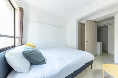 a bedroom with a bed with white sheets and a window at APB\u9ad8\u5186\u5bfa in Tokyo