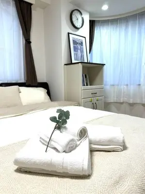 a bedroom with two beds with towels and a clock at Kyo Sai \u6d45\u83492F\u6d45\u8349\u5bfa\u307e\u3067\u5f92\u6b65\u7d0410\u5206 in Tokyo