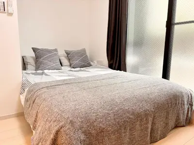 a white bedroom with a bed with gray pillows at IXO Ts1 in Tokyo