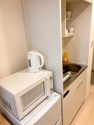 a small kitchen with a microwave and a sink at IXO Ts3 in Tokyo